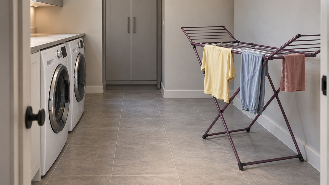 An open plum drying rack holds clothing beside the wall, leaving a clear central walkway to the laundry appliances and storage cabinet.
