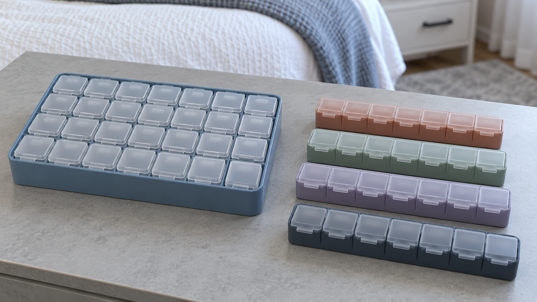 One blue integrated medicine organizer sits beside four separate seven-compartment weekly organizers in terracotta, sage, lavender, and charcoal blue.