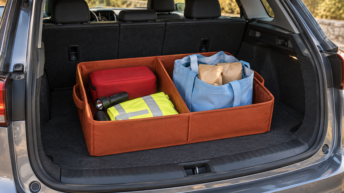 An orange divided trunk organizer separates a red emergency supply case, flashlight, and reflective vest from a blue shopping tote.