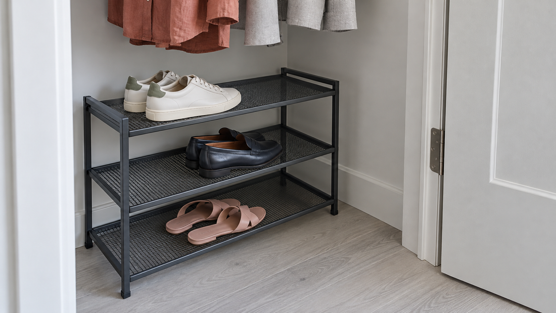 A charcoal three-tier shoe rack fits beneath hanging clothes, with space beside an open hinged closet door.