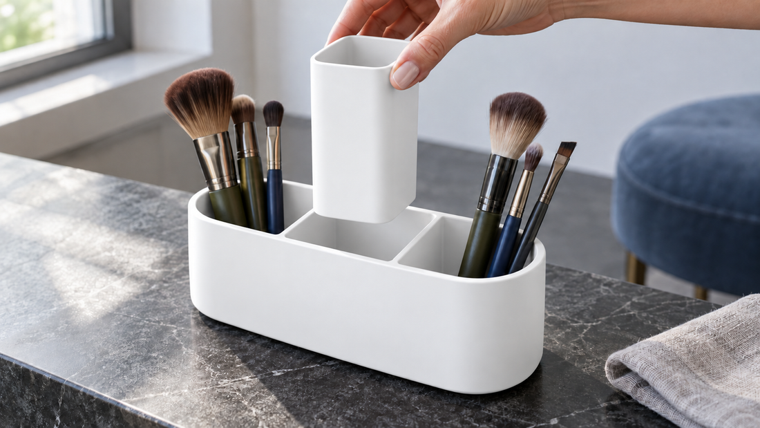 A hand lifts the removable middle insert from a white beauty organizer, with neighboring brushes clear of its removal path.